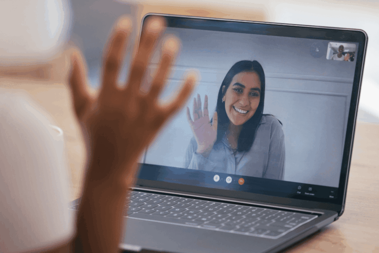 ilustrando artigo sobre integração do SharePoint com Teams temos a foto de uma pessoa em uma videochamada no laptop, acenando para outra pessoa na tela, representando colaboração e conectividade em um ambiente digital.