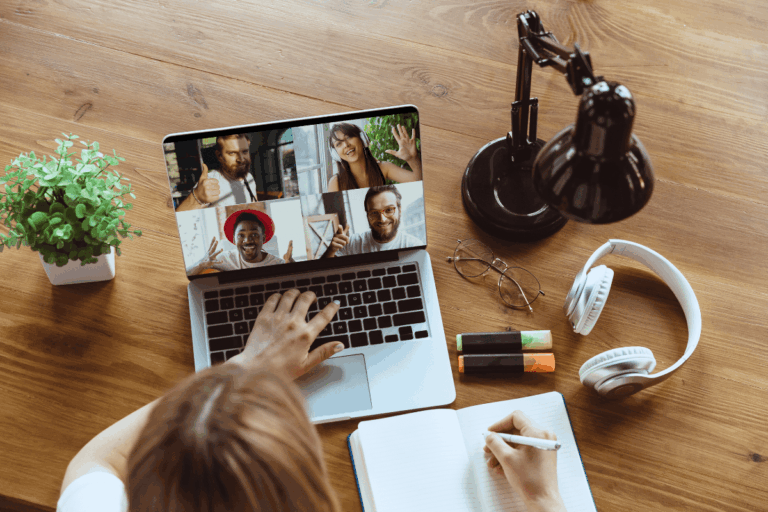 para artigo sobre utilização de SharePoint na melhoria da colaboração remota, foto de uma mulher em sua mesa de trabalho, em casa, fazendo videoconferência com quatro colegas de trabalho pelo computador desktop
