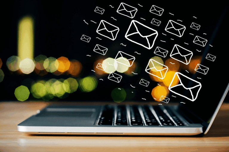 ícones de envelope ilustrados "voam" de notebook à mesa para registrar artigo sobre ferramentas de e-mail integradas a ferramentas de trabalho