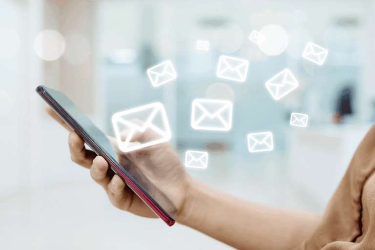 mão de mulher caucasiana segura smartphone de onde emergem ícones de mensagem eletrônica para ilustrar artigo sobre segurança de e-mails no ambiente empresarial